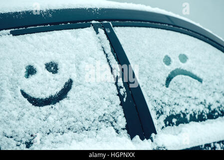 Glückliche und traurige Smiley Emoticon im Schnee auf Autoscheiben, Winter Saison Freude und Glück-Konzept Stockfoto