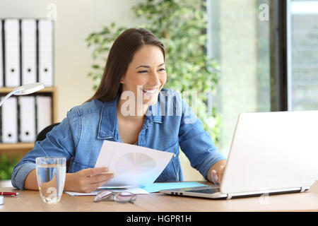 Unternehmer, die hält ein Papier arbeiten vergleichen Dokumente online mit einem Laptop im Büro Stockfoto
