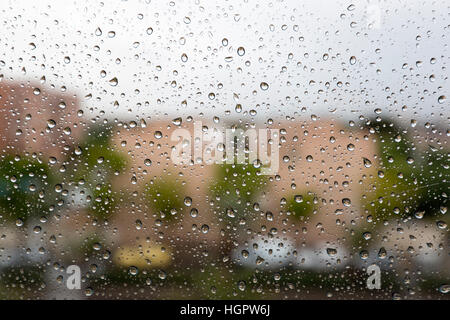 Regentropfen auf ein Fensterglas einer Wohnung, wo Teil der Stadt im Hintergrund zu sehen ist Stockfoto