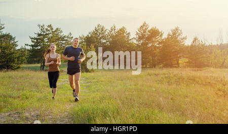 Junges Paar Joggen im Freien. Sonnenuntergang, Blendung durch die Sonne leuchtet ein paar Stockfoto