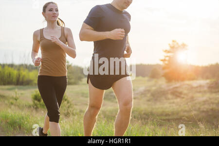 Junges Paar bei Sonnenuntergang im freien laufen. Sonneneruption leuchtet ein paar zurück. Stockfoto