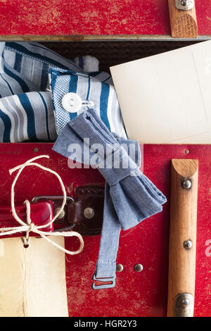 Detail eines Vintage Koffer mit Tag und mehrere Objekte von einem Mann oder ein Junge an einer Reise: Fliege, Pyjama und Postkarte Stockfoto