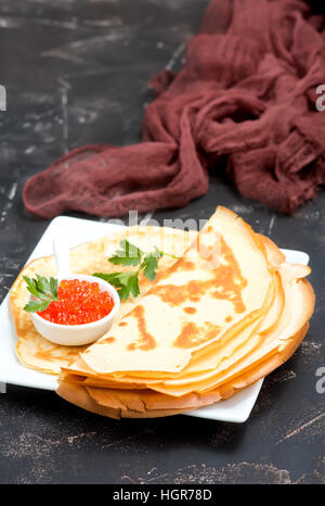 Pfannkuchen mit Kaviar auf dem Teller und auf einem Tisch Stockfoto