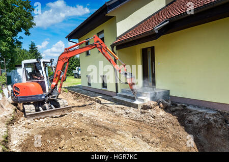 Ein Einfamilienhaus wird mit Hilfe eines Baggers wieder aufgebaut Stockfoto