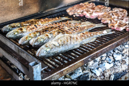 Fisch und Steak auf dem Holzkohle grill zusammen. Startseite Grill-Picknick mit Dorade und Schweinekoteletts Stockfoto