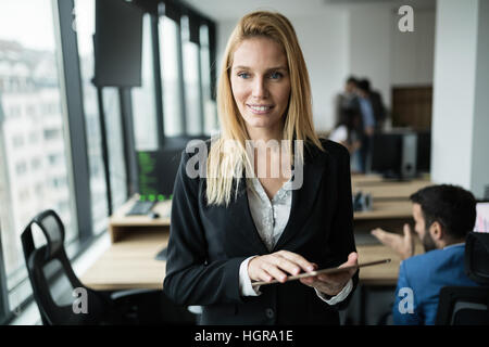 Schöne blonde Geschäftsfrau Holding Tablet im modernen Büro Stockfoto