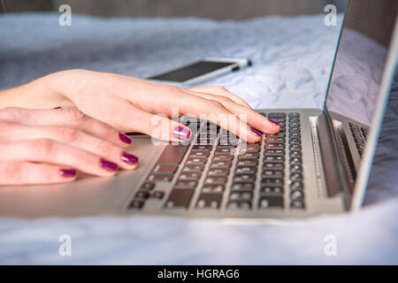 Close-up Teilansicht der jungen Frau mit Laptop am Bett Stockfoto