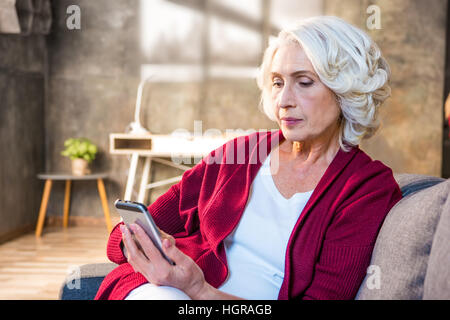 Porträt von senior Frau mit Smartphone sitzend auf sofa Stockfoto