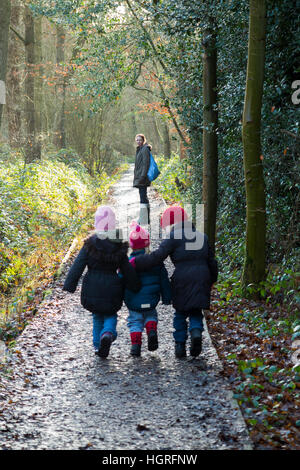 Mutter & 3 Kinder drei Kinder Töchter gehen / laufen auf schlammigen Weg / im Schlamm auf Gehweg Weg Fuß Weg Fußweg Esher UK Stockfoto