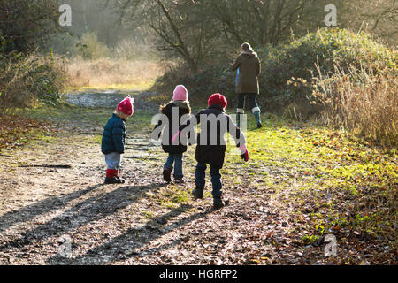 Mutter & 3 Kinder drei Kinder Töchter gehen / laufen auf schlammigen Weg / im Schlamm auf Gehweg Weg Fuß Weg Fußweg Esher UK Stockfoto