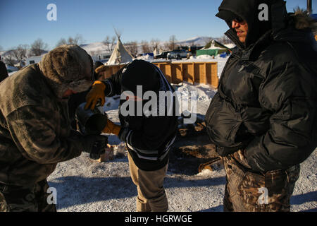 Kanonenkugel, USA. 12. Januar 2017. Manape Lamere Mdewakanton, Isanti und Ihanktonwan Stämme (links) und John Eagleshield Jr. von der Standing Rock Sioux Stammes (Mitte) sammeln Sie Asche aus der erloschenen heiligen Feuer auf den Oceti Oyate Camp, früher bekannt als die Oceti Sakowin Camp in der Nähe der Standing Rock Indian Reservation nördlich von Kanonenkugel, North Dakota. Bildnachweis: ZUMA Press, Inc./Alamy Live-Nachrichten Stockfoto