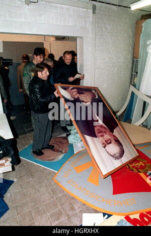 Archiv - Archivierung Bild datiert 15.01.1990 zeigt die DDR-Bürger mit gerahmten Bildern des sowjetischen Führers Leonid Brezhnev und die ostdeutschen Parteichef Erich Honecker in der Zentrale des Amtes für nationale Sicherheit in Ost-Berlin, Deutschland. Demonstranten hatten das Gebäude kurz vor, stürmten so versiegeln das Schicksal der ostdeutschen Sicherheitsdienste besser bekannt als die Stasi. Foto: Wolfgang Kumm/dpa Stockfoto