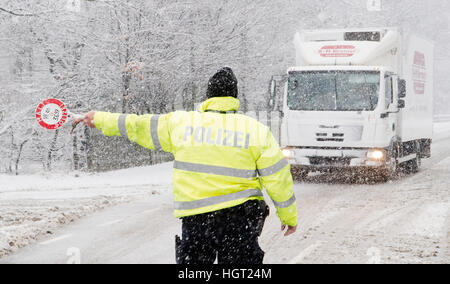 Bad Harzburg, Deutschland. 13. Januar 2017. Ein Polizist hält ein LKW mit einer Straße in einem Schneesturm ohne Schneeketten auf seine Reifen in Bad Harzburg, Deutschland, 13. Januar 2017. Das Sturmtief "Egon" verantwortete starke Stürme und Schnee in ganz Deutschland. Foto: Julian Stratenschulte/Dpa/Alamy Live News Stockfoto