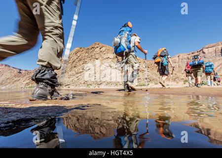Wanderer mit Rucksäcken überqueren Fish River, Fish River Canyon, Namibia Stockfoto