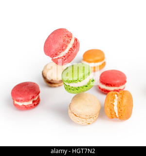 Verschiedene Arten von Makronen in Bewegung fallen oder fliegen auf weißem Hintergrund. Traditionelle französische Dessert isoliert Stockfoto