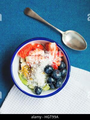 Frühstück Obst Salatschüssel. Gesundes Frühstück für jedes Alter. Antikes Besteck, blaue und weiße Keramikschale. Stockfoto