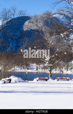 Bergsee in Winterlandschaft mit Neuschnee auf Holzbänken. Winterlandschaft. Stockfoto