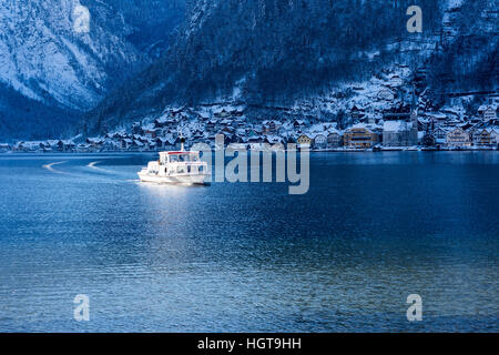 Boot-Segeln am Bergsee mit schönen Schnee bedeckt Dorf. Winterlandschaft. Stockfoto