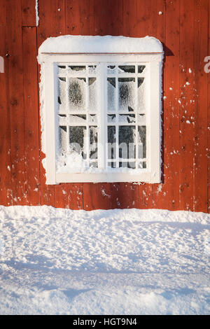 Alten frostigen Fenster auf einer roten Wand mit Schnee. Roslagen, Schweden, Skandinavien. Stockfoto