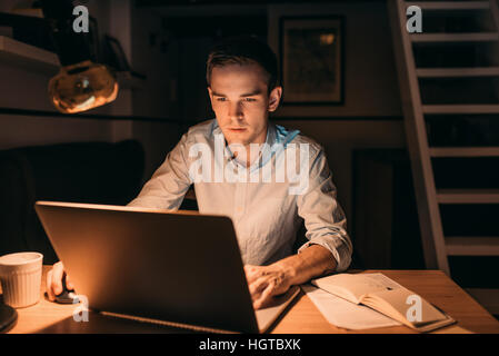 Junge Unternehmer, die in den späten Abend auf einem Laptop arbeiten Stockfoto