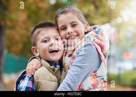 Glücklich Geschwister umarmen außerhalb Stockfoto