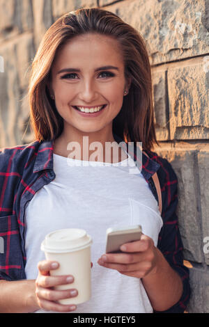 Lächelnde junge Frau mit einem Handy in der Stadt Stockfoto