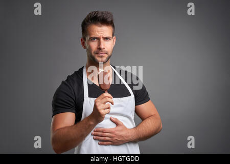 Ein hübscher Junge Barista Mann Magenschmerzen beim Essen ein Eis Stockfoto