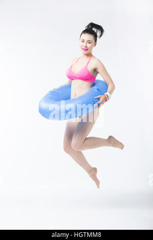 Junge schlanke Frau im Bikini springen tragen ein Rohr Stockfoto