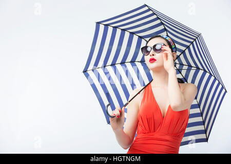 Porträt der jungen Frau im Badeanzug und Sonnenbrille hält Regenschirm nachschlagen Stockfoto