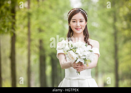 Junge lächelnde Braut hält Blumen im freien Stockfoto