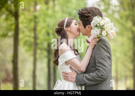Seitenansicht des jungen romantische Hochzeitspaar küssen im freien Stockfoto