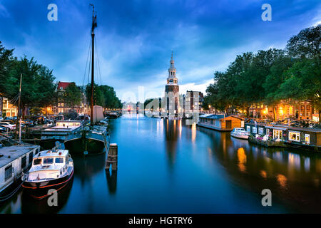 Schöne Nacht in Amsterdam. Nacht Beleuchtung von Gebäuden und Boote in der Nähe der Wasser in den Kanal. Stockfoto