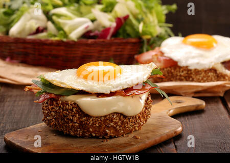 Sandwich mit Käse, Speck und Spiegelei auf hölzernen Hintergrund Stockfoto