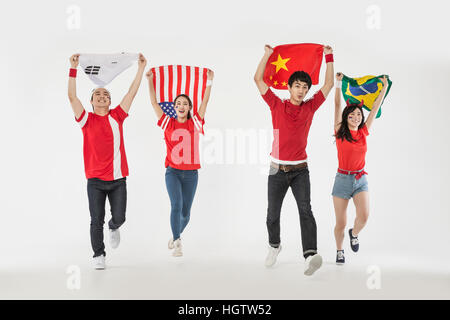 Junge lächelnde Cheerleader laufen mit Nationalflaggen Stockfoto