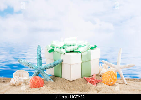 Muscheln und Geschenkbox am Strand gegen Sommer Meer Stockfoto