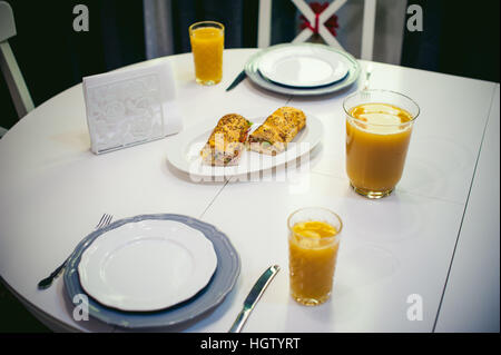 Frühstück-Sandwich und Pfirsich-Saft. in der helle Innenraum der Küche in einem Teller auf der Tisch ist ein Sandwich-Saft in ein Glas gegossen Stockfoto