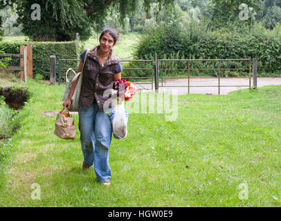 Frau mit mehreren Taschen und ein paar frische Blumen Stockfoto