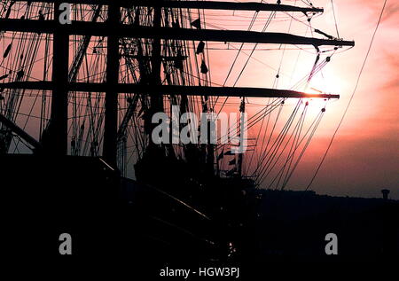 AJAXNETPHOTO. 1989. ROUEN, FRANKREICH. -GROßSEGLER VERSAMMELN SICH AUF SEINE - SUN SETS HINTER DER WERFTEN UND DIE MASTEN DER SEGELSCHIFFE VOR ANKER IN DER STADT FÜR DIE "VOILE DE LA LIBERTE" PARADE DER SEGEL.  FOTO: JONATHAN EASTLAND/AJAX REF: M7 1989 Stockfoto