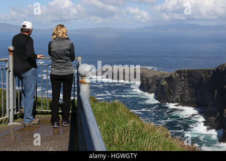 Mann und Frauen machen Fotos von der Westküste Irlands mit weißen Wellen am Fogher Klippen, Valentia Island, County Kerry, Irland. Stockfoto