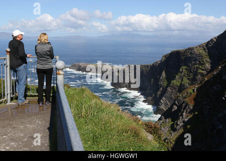 Mann und Frauen heraus, die von den Klippen Sicht in Irland mit weißen Wellen,, blauen Himmel bei der fogher Klippen, Valentia Island, County Kerry, Irland. Stockfoto