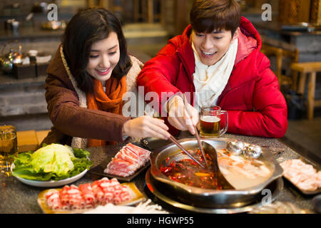 Junges Paar mit Abendessen im Hotpot restaurant Stockfoto