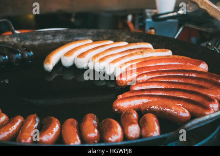 Würste gebraten auf einem Frying Pan. Traditionelle Weihnachten Gericht von Street Food auf Straßen Europas im Winter während der Weihnachtsferien. Stockfoto