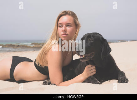 Blonde Teenager mit ihr Haustier Labrador am Strand. Stockfoto