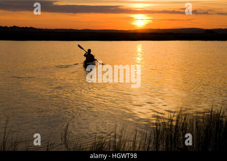 Eine Frau Kajaks bei Sonnenuntergang in den Connecticut River in Old Lyme, Connecticut. Stockfoto