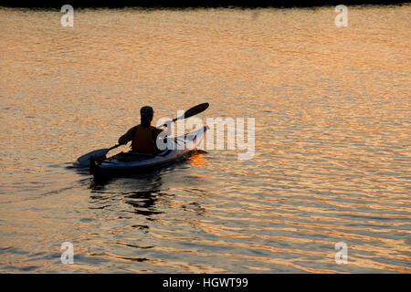 Eine Frau Kajaks bei Sonnenuntergang in den Connecticut River in Old Lyme, Connecticut. Stockfoto