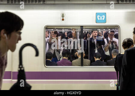 Menschen, die mit ihren Handys während der Fahrt über Tokio u in der Rush Hour. Tokyo, Japan Stockfoto