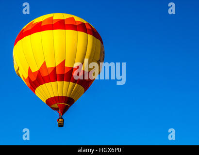Roten & gelb Heißluft-Ballon vor blauem Himmelshintergrund Stockfoto
