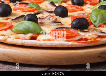 Pilz-Pizza mit Oliven, Tomaten und Basilikum auf dem Tisch. horizontale Stockfoto