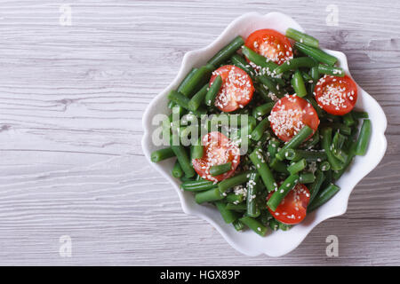 Salat von grünen Bohnen, Kirschtomaten und Sesam in einem schönen weißen Teller. horizontale. Ansicht von oben Stockfoto