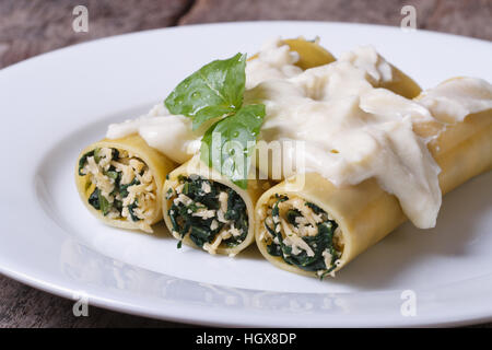 Cannelloni-Nudeln gefüllt mit Spinat und Käse mit Bechamel-Sauce und Basilikum auf dem Tisch Stockfoto